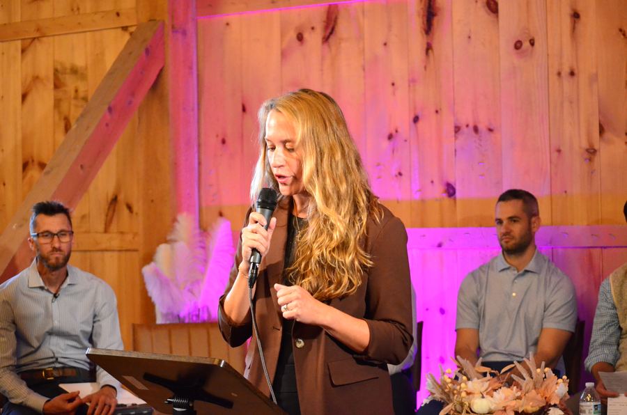 Brooke Schnorr speaking, with the other speakers seated behind her