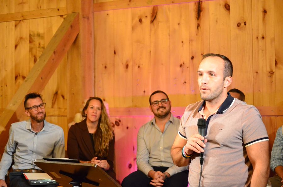 Nick Liberatore speaking, with the other speakers seated behind him